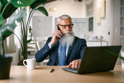 Young man using mobile phone while sitting on table