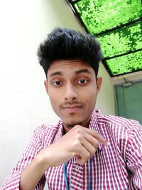 Portrait of young man standing against wall