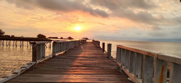 Pier over sea against sky during sunset