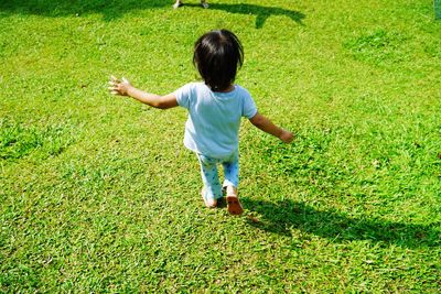 Rear view of girl walking on grassy field