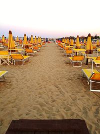 Empty chairs on beach against clear sky