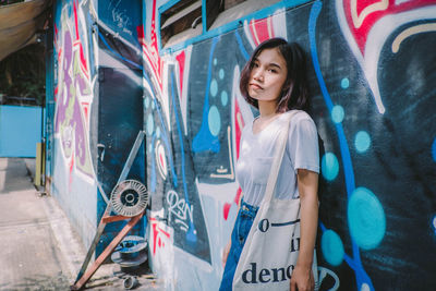 Portrait of smiling girl standing on graffiti