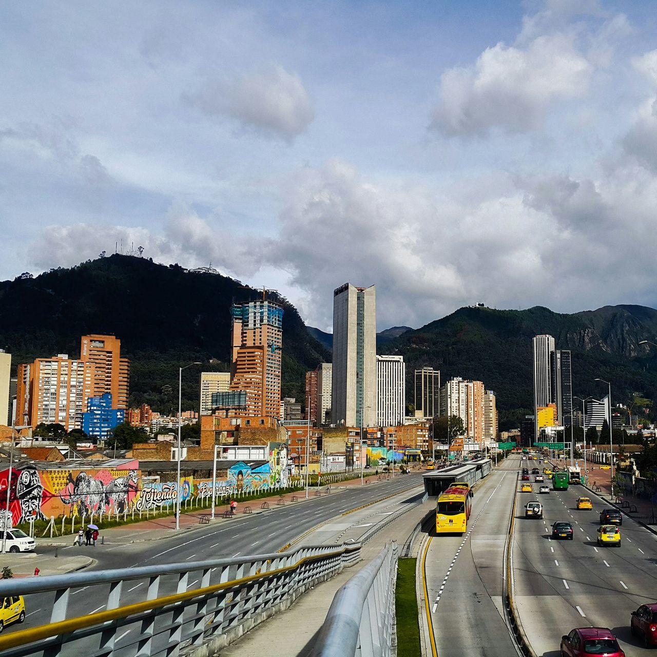 transportation, city, building exterior, architecture, car, built structure, road, street, sky, land vehicle, mode of transport, road marking, cityscape, city life, high angle view, cloud - sky, traffic, city street, the way forward, illuminated