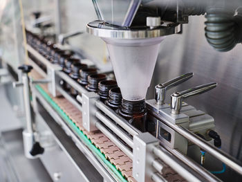 Row of plastic bottles on conveyor of filling machine at modern pharmaceutical manufacturing plant