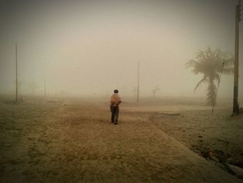 Rear view of boy on sand at beach