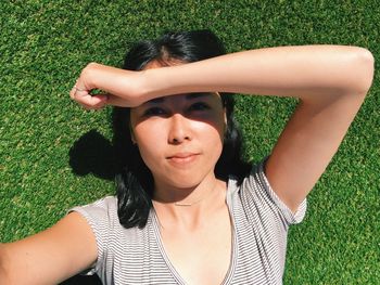 Beautiful woman shielding eyes while lying on field