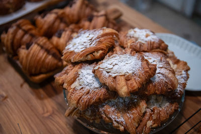 Homemade croissant with sliced almond on glass and on wood background at cafe, bakery concept