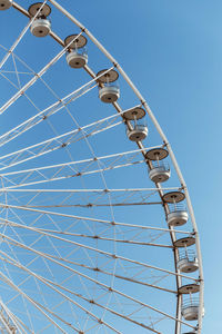 Low angle view of ferris wheel against clear blue sky