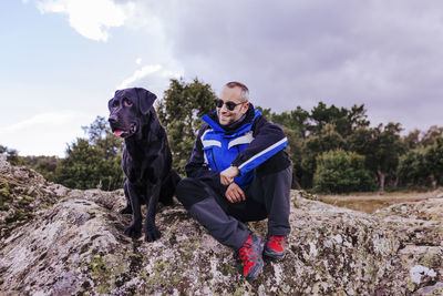 Man sitting with dog on rock