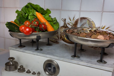 Close-up of coins and various vegetables on weight scale