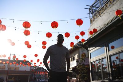 Low angle view of young man standing against lanterns in city