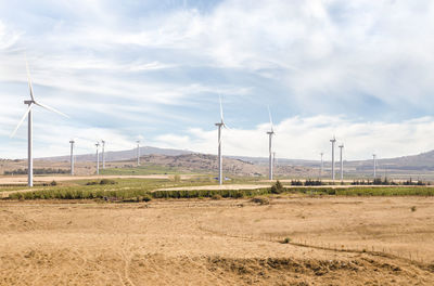 Windmills on field against sky