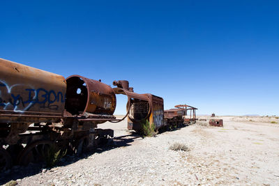 Abandoned train on railroad track against clear blue sky