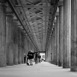 People standing on walkway below bridge