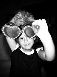 Portrait of girl holding heart shaped sunglasses