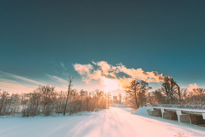 Snow covered field against sky during sunset