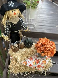 A mini scarecrow sitting on a hay bale on a warm fall day. 