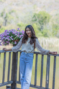 Portrait of young woman standing against railing