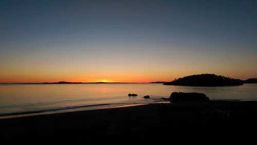 Scenic view of beach against sky at dusk