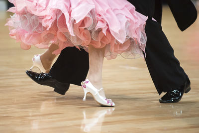 Low section of couple dancing on hardwood floor