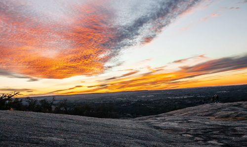 Scenic view of landscape against dramatic sky during sunset
