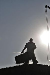 Silhouette man sitting on field against sky