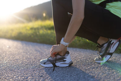 Close-up of sportive young woman tying her shoes