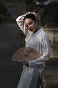 Young woman holding umbrella standing outdoors