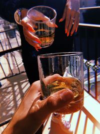 Friends holding whiskey glasses in balcony