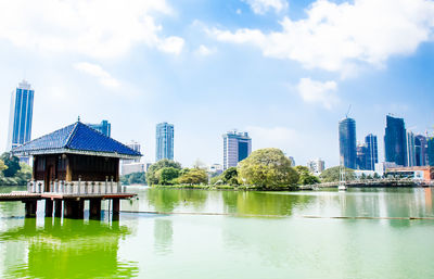 Buildings by river against sky in city