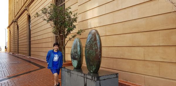 Rear view of boy standing against wall in city