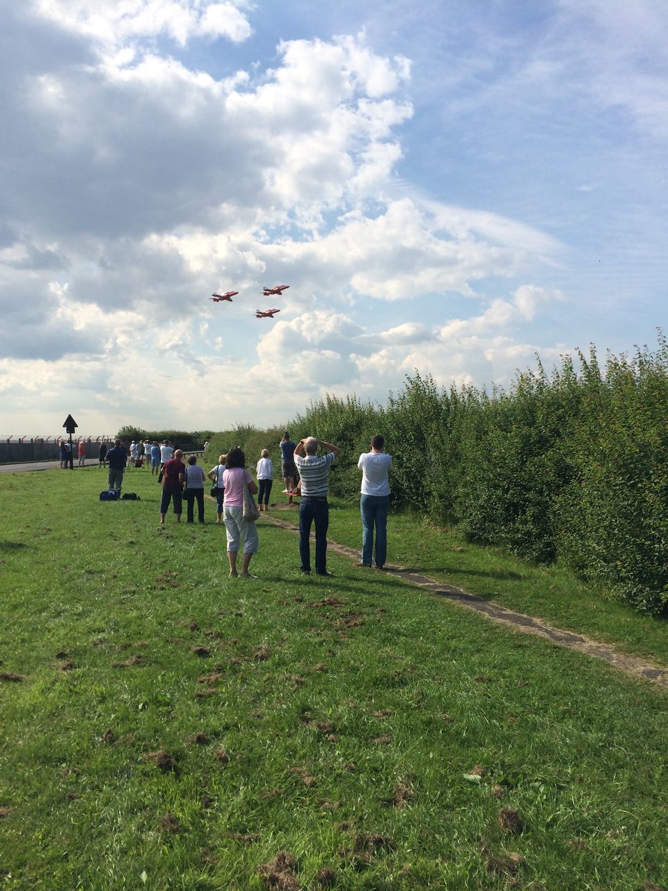 cloud - sky, sky, grass, flying, plant, nature, real people, group of people, transportation, men, field, air vehicle, land, day, airplane, people, leisure activity, green color, mode of transportation, outdoors