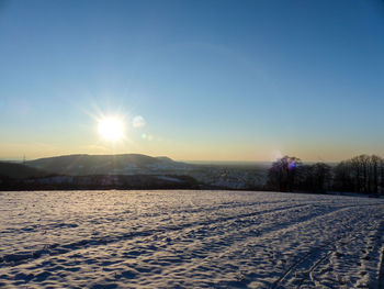 Scenic view of snow field against clear sky during sunset