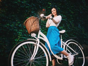 Portrait of woman with bicycle on tree