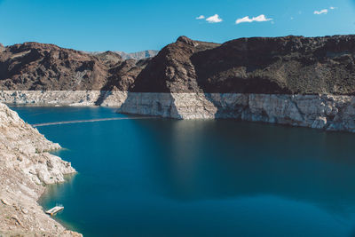 Scenic view of lake by mountains against blue sky