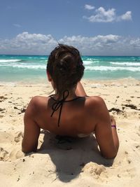 Rear view of woman on beach against sky