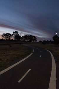 Road by trees against sky