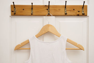 Close-up of tank top hanging on hook against door