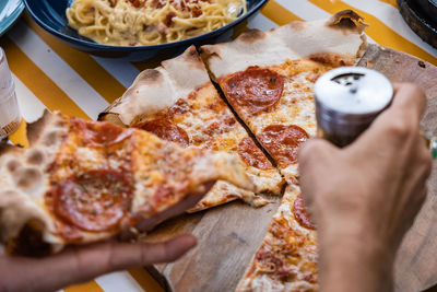 High angle view of hand holding pizza on table