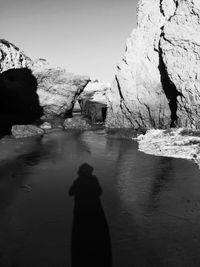 Man standing on rock by sea against clear sky