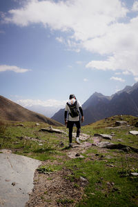 Rear view of man walking on mountain against sky