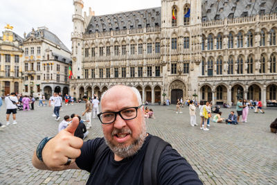 Cheerful tourist's thumbs-up selfie, exploring brussels' heart