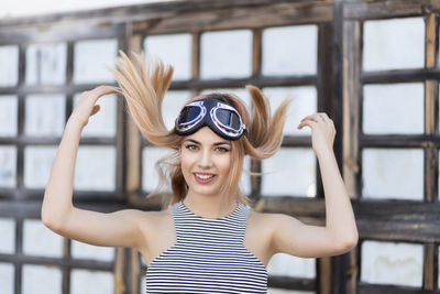 Portrait of smiling young woman with long blond hair wearing flying goggles