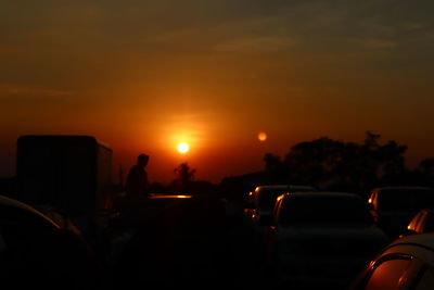 Silhouette people against orange sky during sunset