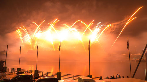 Firework display over sea against sky at night