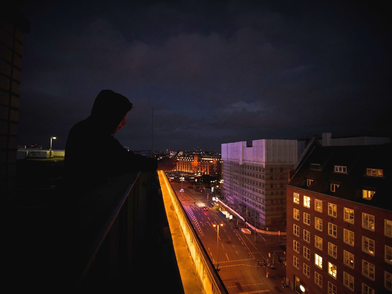 MAN ON ILLUMINATED STREET AMIDST BUILDINGS IN CITY