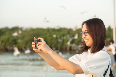 Close-up of woman photographing with mobile phone outdoors