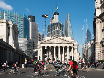 People on city street by buildings against sky