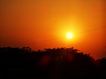 Silhouette trees against orange sky during sunset