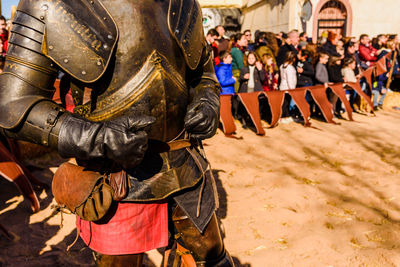 Midsection of man in warrior costume against crowd on street